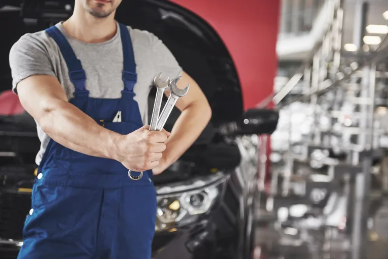mecánico con una llave y un automovil detras